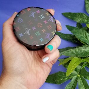 Hand holding patterned compact on purple background