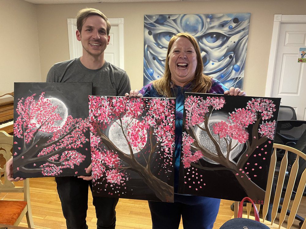 Smiling artists holding cherry blossom paintings