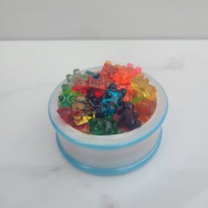 Multicolored gummy bears on white surface.