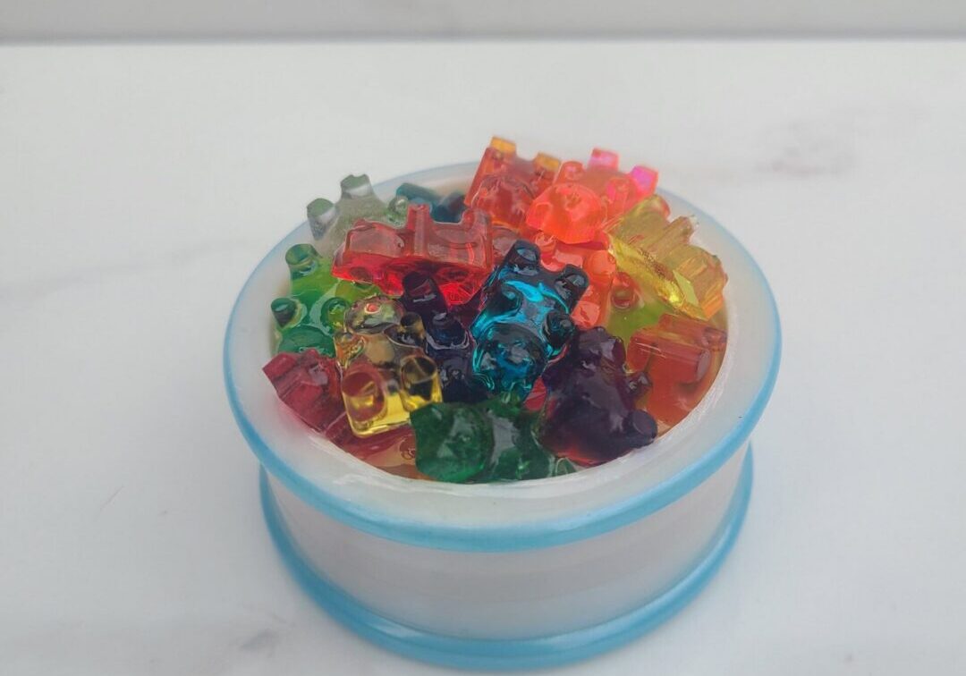 Multicolored gummy bears on white surface.